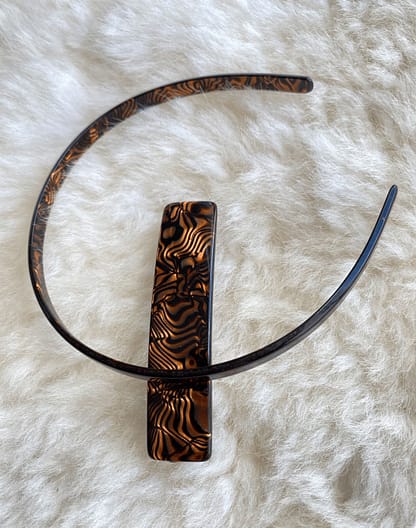 overhead view of a vintage tortoise patterned headband and barrette, with the headband lying on its side to show the pattern on the underside