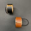 two leather and metal ponytail covers with elastic, shown in black and tan leeather