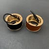 two leather and metal ponytail covers with elastic, shown in black and tan leeather