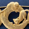 Close-up of a signed vintage JJ Jonette gold-tone brooch, featuring two cats interacting on a circular ring.