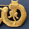 Close-up of a signed vintage JJ Jonette gold-tone brooch featuring a cat perched atop a circular ring.