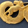 Close-up of a signed vintage JJ Jonette gold-tone cat brooch, showing the textured details of a cat reaching across a circular ring.