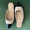 Top view of Banana Republic beige and black ballet mules on a green background, highlighting the backless design and pointed toe.