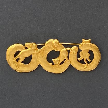 Signed vintage JJ Jonette gold-tone brooch featuring four playful cats climbing on interconnected circular rings.