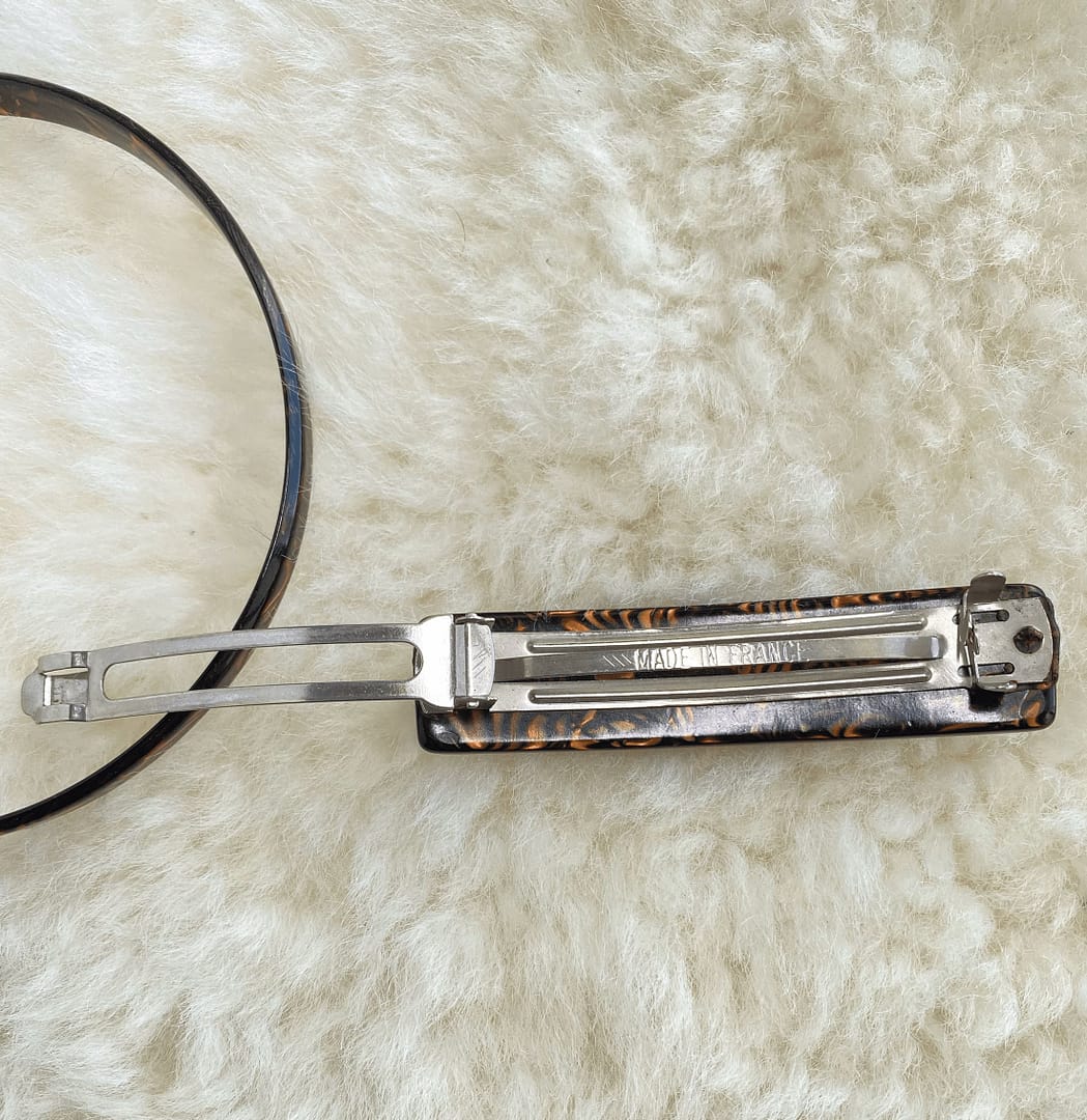 overhead view of a vintage tortoise patterned headband and barrette, showing the underside of the barrette with the clasp open.