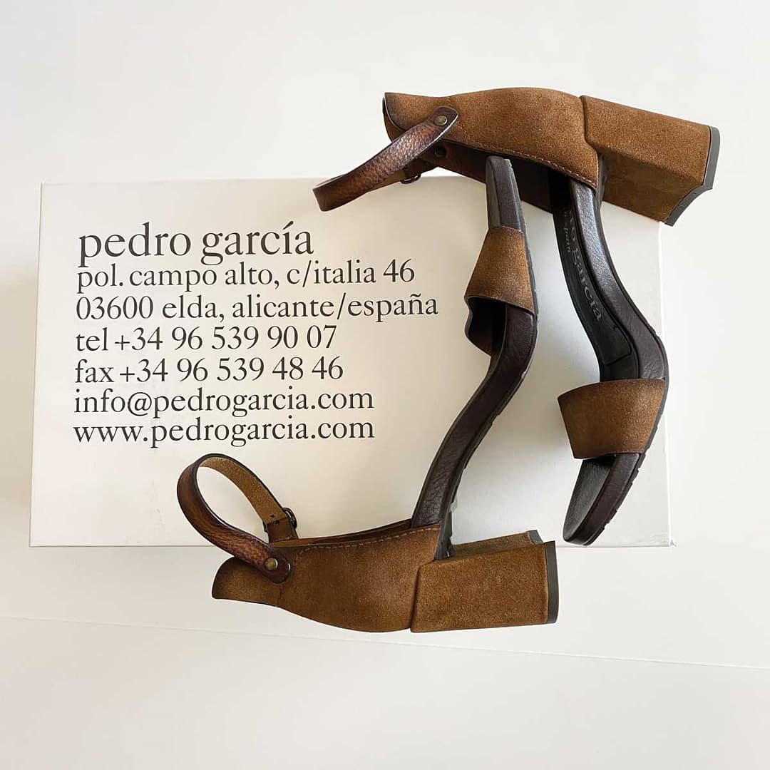 Overhead view of shoes in profile, showing ankle strap and block heels, resting on the printed top of the Pedro Garcia shoebox