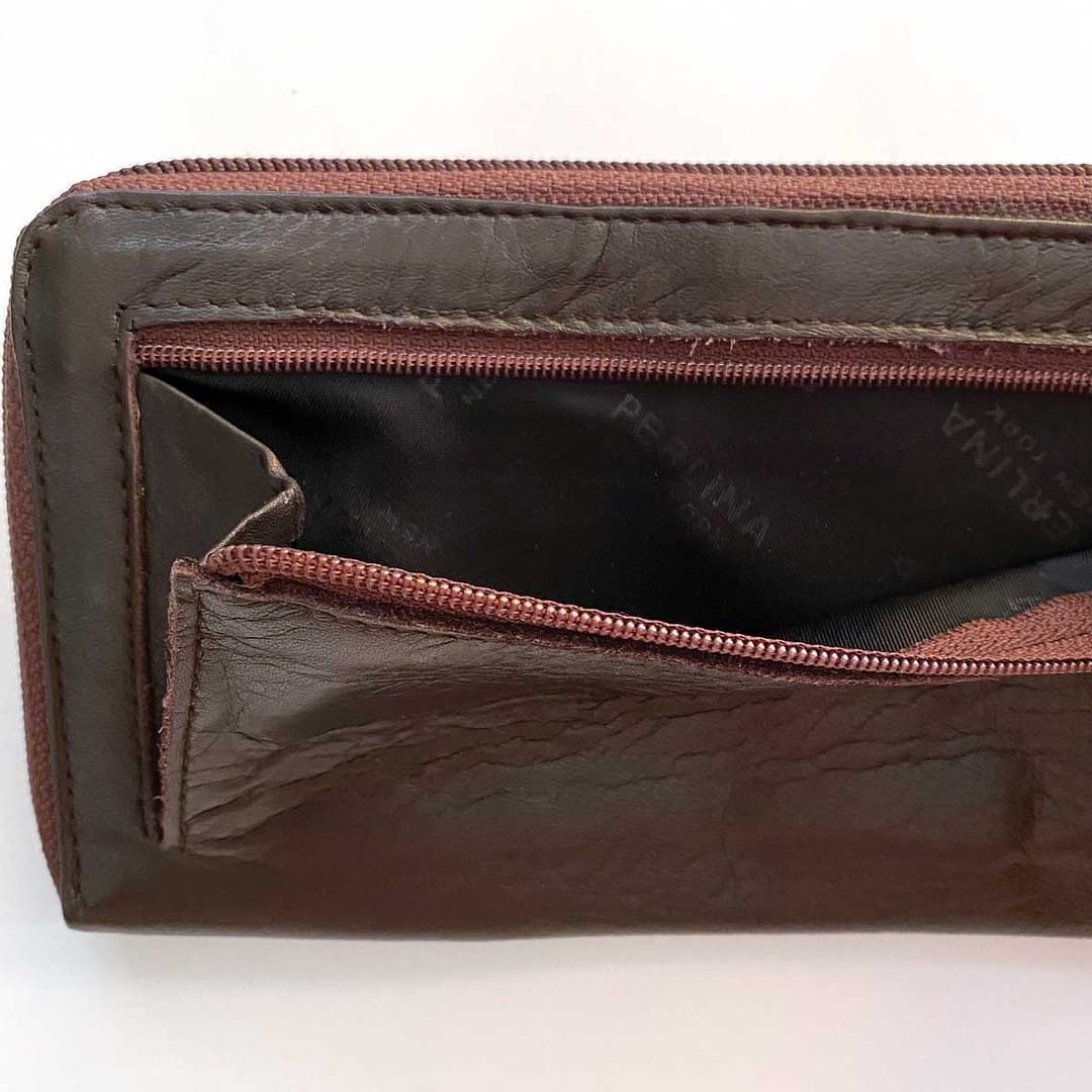 Closeup of the unzippered external zipper pocket on the back of the wallet, showing the satin logo lining and the pocket gusset width.