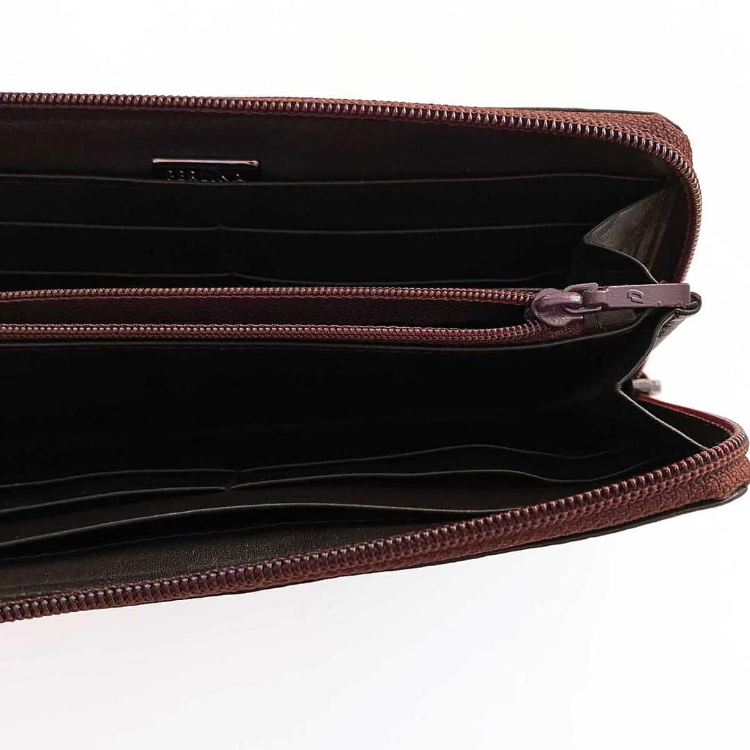 Close up view of a vintage Perlina large leather wallet showing the unzippered inside credit card and bill compartments of the wallet and the internal zipper pocket.