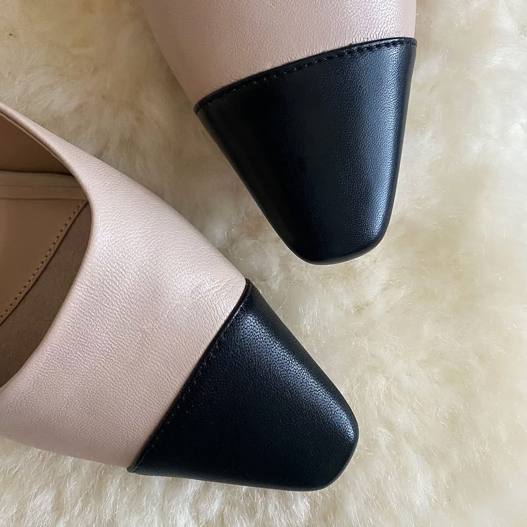 Top view of Banana Republic beige and black ballet mules on a cream background, highlighting the black toe caps.