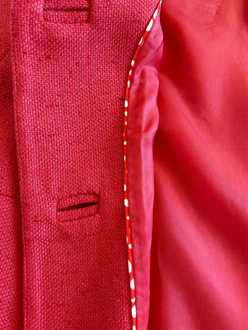 closeup of buttonhole and lining detail of a red Rena Lange silk jacket