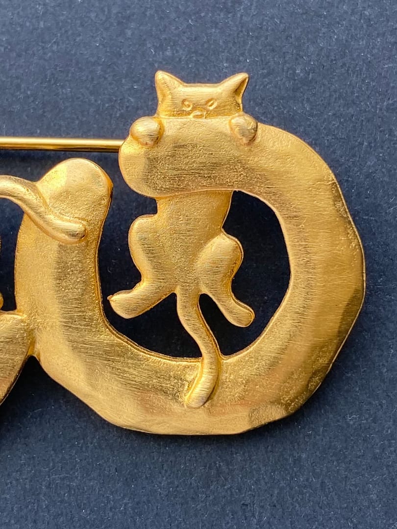 Close-up of a signed vintage JJ Jonette gold-tone brooch featuring a cat perched atop a circular ring.