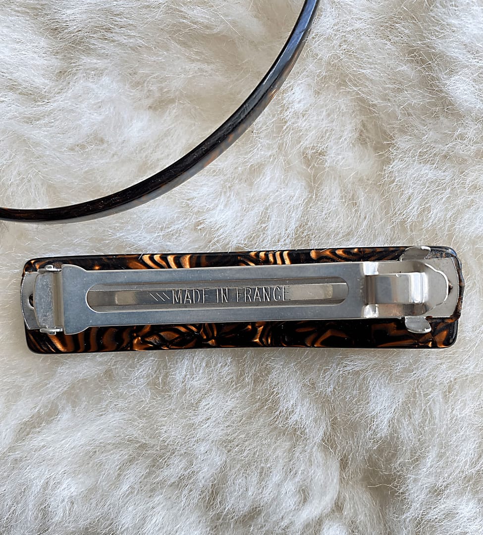 overhead view of a vintage tortoise patterned headband and barrette, showing the underside of the barrette that reads Made in France.